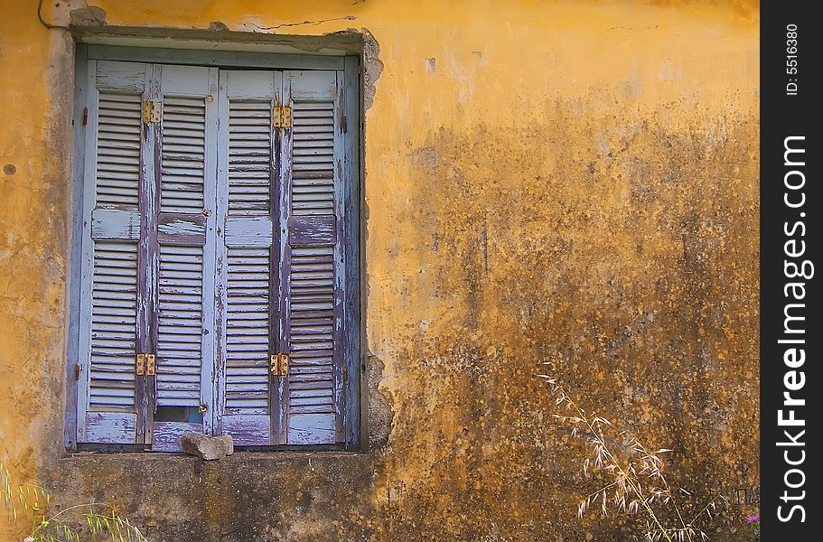 Blue Window Shuttered On Yellow Wall.