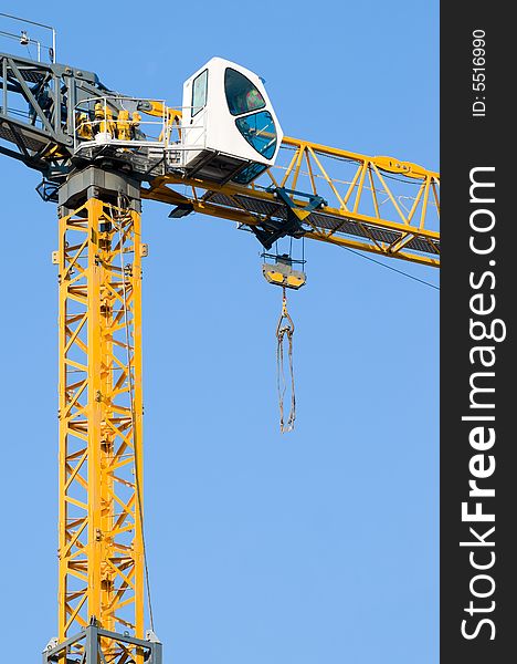 High yellow construction crane against the clear blue sky, lot of copyspace