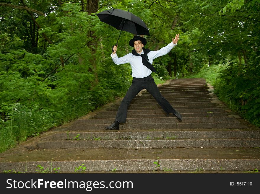 The man with umbrella jumping on a stair. The man with umbrella jumping on a stair.