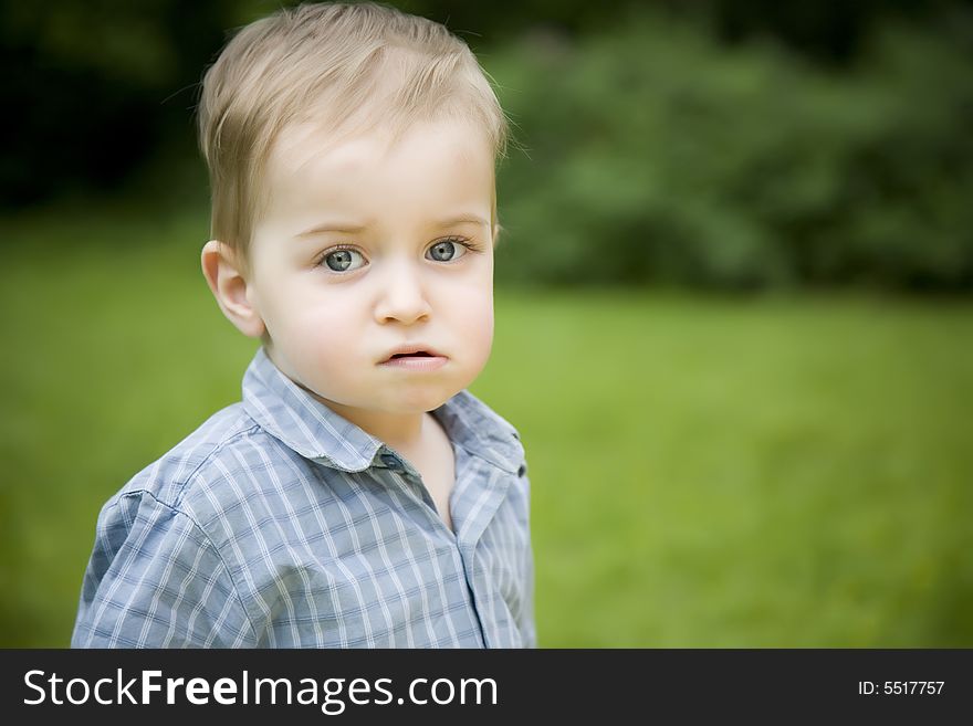 Serious Little Boy On The Nature Background. Serious Little Boy On The Nature Background