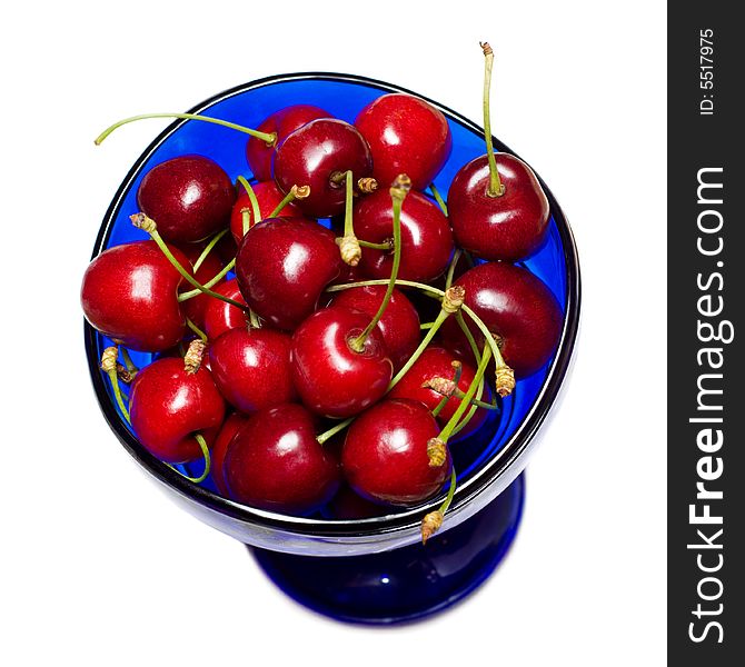 Ripe fresh sweet cherries in the cup of blue glass, isolated on white. Ripe fresh sweet cherries in the cup of blue glass, isolated on white