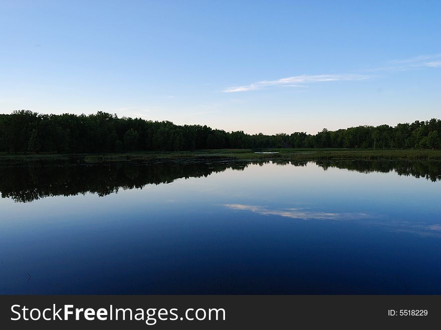 Sky and forest reflected onto lake. Sky and forest reflected onto lake