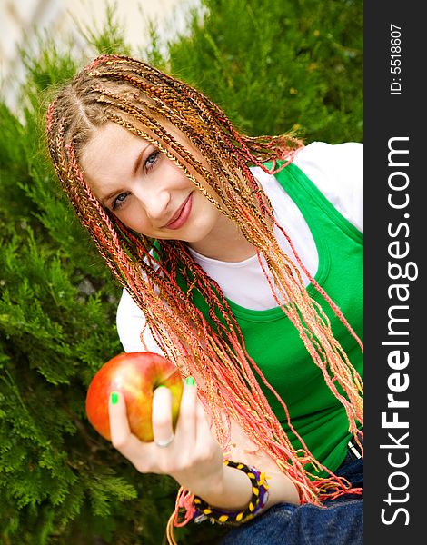 Teenager girl with red apple on the green grass