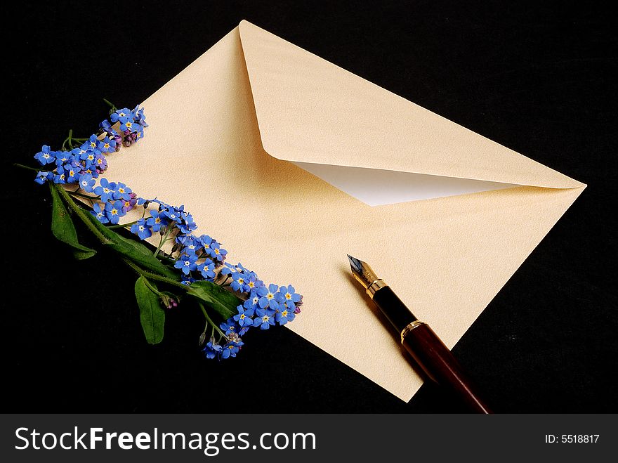 Envelope with blue flowers on black backround with pen. Envelope with blue flowers on black backround with pen