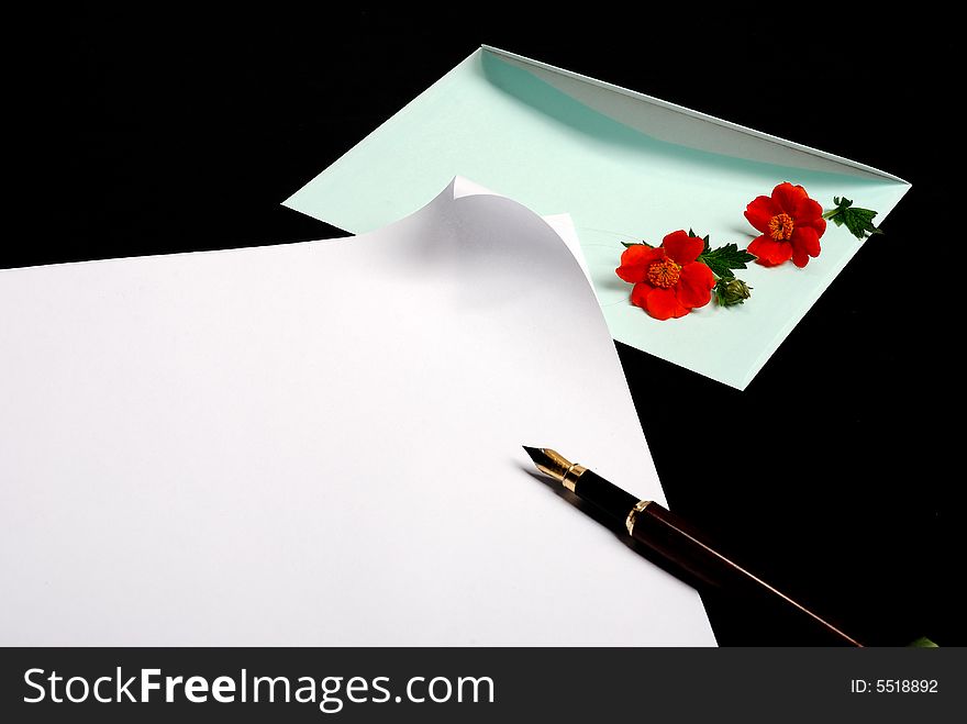 Envelope with blue flowers on black background with pen and piece of paper - place for additional text or logo. Envelope with blue flowers on black background with pen and piece of paper - place for additional text or logo