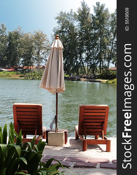 Deck chairs overlooking a lake at a tropical resort- travel and tourism.