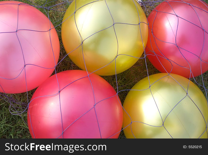 Pure balloons on the grass,they are under the netting.