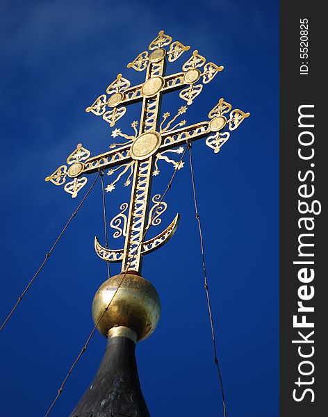 Gold Christian cross on a background of the blue sky. Gold Christian cross on a background of the blue sky