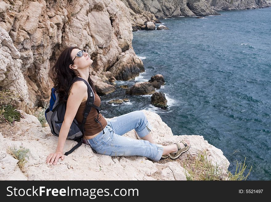 Hiker siting on a stones above the sea coast