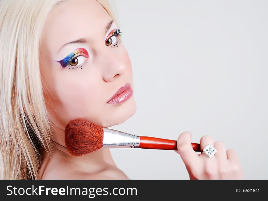 Beautiful girl with bright make-up, looks through a shoulder and holds a brush in a hand. Beautiful girl with bright make-up, looks through a shoulder and holds a brush in a hand