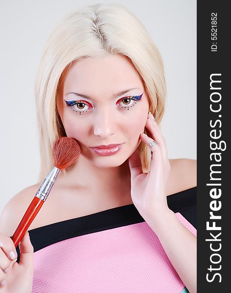 Beautiful girl with bright make-up, looks through a shoulder and holds a brush in a hand. Beautiful girl with bright make-up, looks through a shoulder and holds a brush in a hand