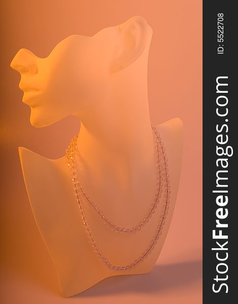 Crystal necklace shown on a frosted glass display standl shot with orange gel sheet for glow effect. Crystal necklace shown on a frosted glass display standl shot with orange gel sheet for glow effect