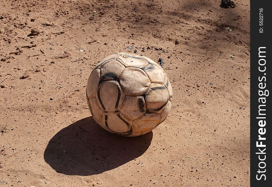Used up deflated soccer ball in the dirt. Used up deflated soccer ball in the dirt