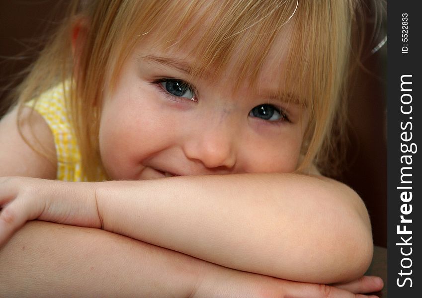 Little girl smiling while resting head on crossed arms. Little girl smiling while resting head on crossed arms