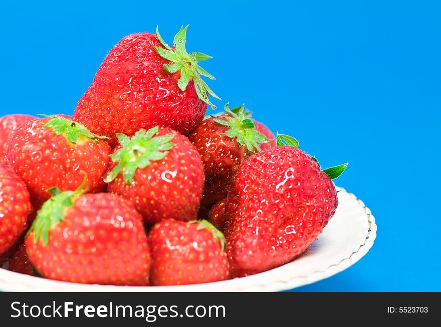 Fresh strawberries on plate on blue background