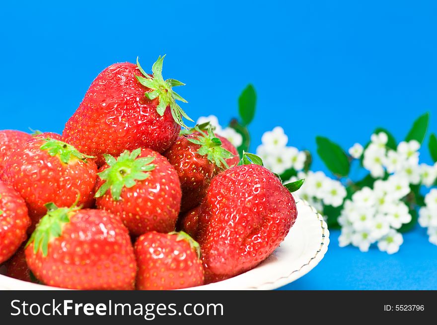 Fresh strawberries and flowers on blue background