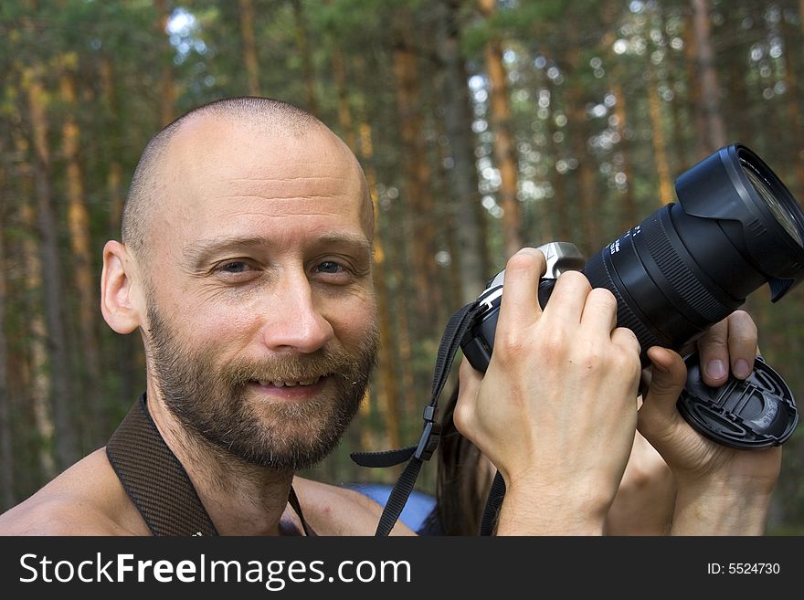 Cheerful smiling photographer in a forest in a sunny day. Close-up. Cheerful smiling photographer in a forest in a sunny day. Close-up