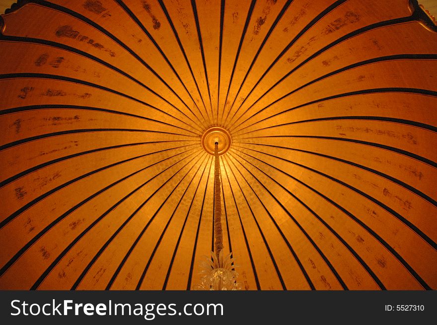 Close up on a round gold cupola ceiling, with a long chandelier