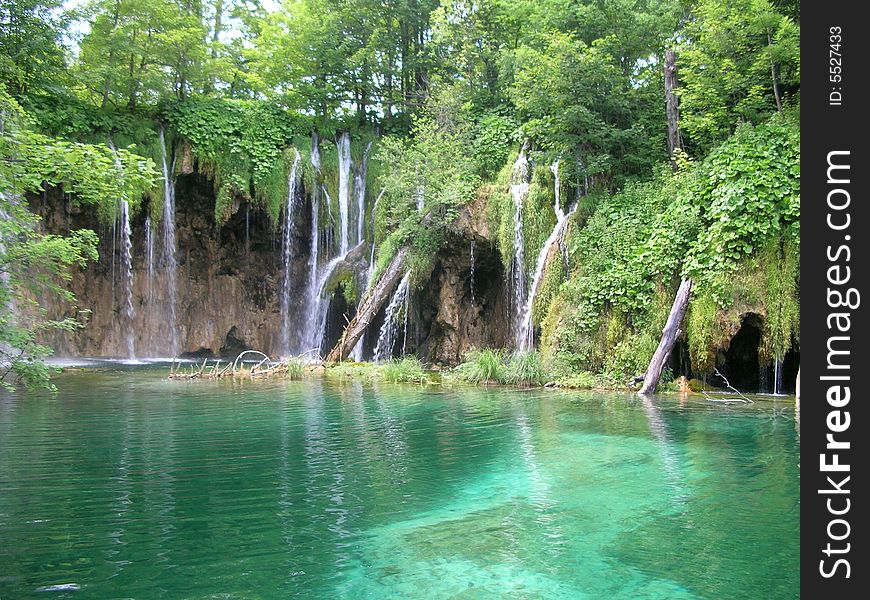 Picture of a tropical lake with green trees, waterfalls clear water and sharp cliffs. Picture of a tropical lake with green trees, waterfalls clear water and sharp cliffs