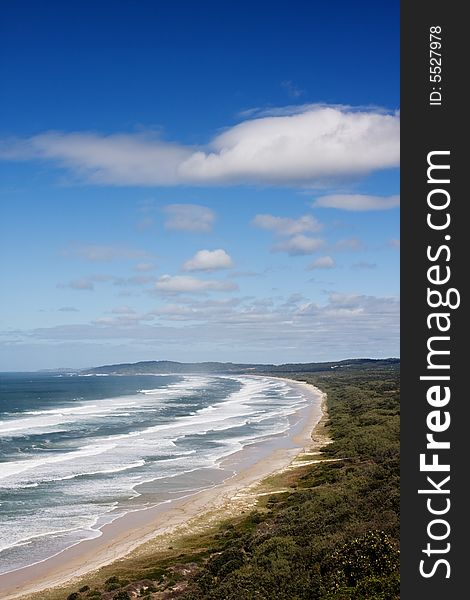 Beutifull coastline and wave hitting the beach. Green landscape at the distance. Byron Bay - Australia