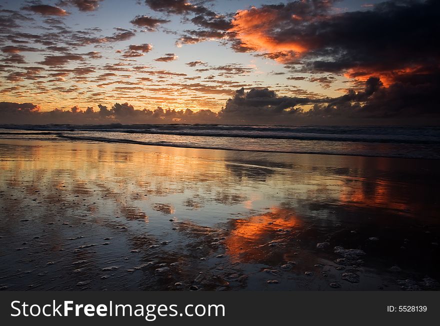 Sunset over a beautiful sandy beach, Very clear and bright perspective with clouds layers that accentuate the horizon, while several sun rays penetrates the clouds. Sunset over a beautiful sandy beach, Very clear and bright perspective with clouds layers that accentuate the horizon, while several sun rays penetrates the clouds.