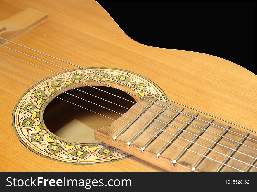 Acoustic wooden yellow six-string guitar on a black background.