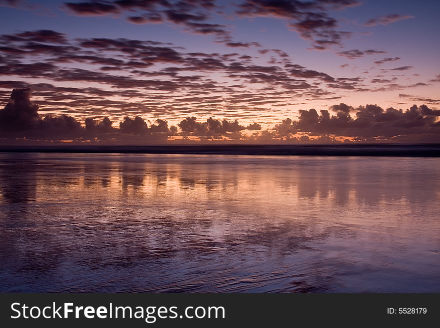 Sunset over a beautiful sandy beach, Very clear and bright perspective with clouds layers that accentuate the horizon, while several sun rays penetrates the clouds. Sunset over a beautiful sandy beach, Very clear and bright perspective with clouds layers that accentuate the horizon, while several sun rays penetrates the clouds.