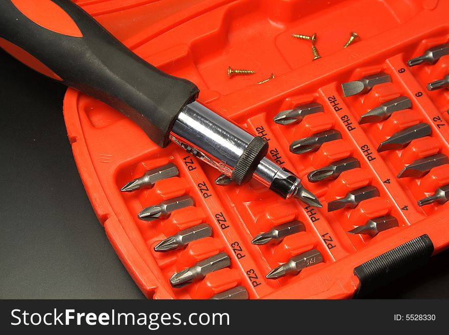 Screwdriver with a set of replaceable nozzles and screws in a case.