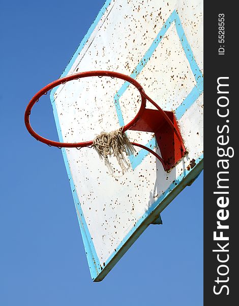 Old basketball hoop on clear blue sky.