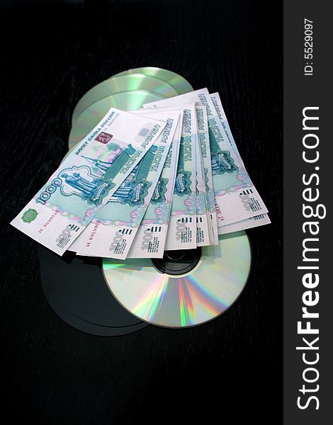 Bills by value 1000 roubles and computer disks for keeping of information on dark background