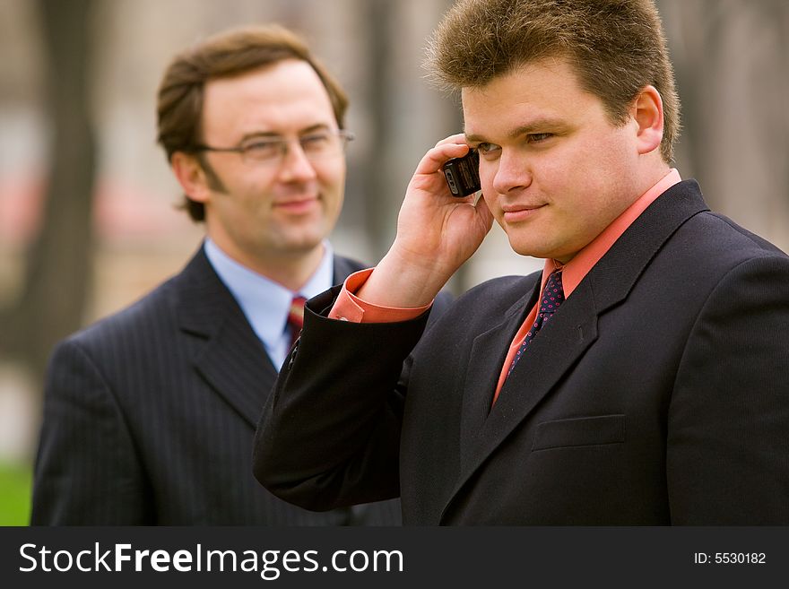 Two businessmen, one making a call