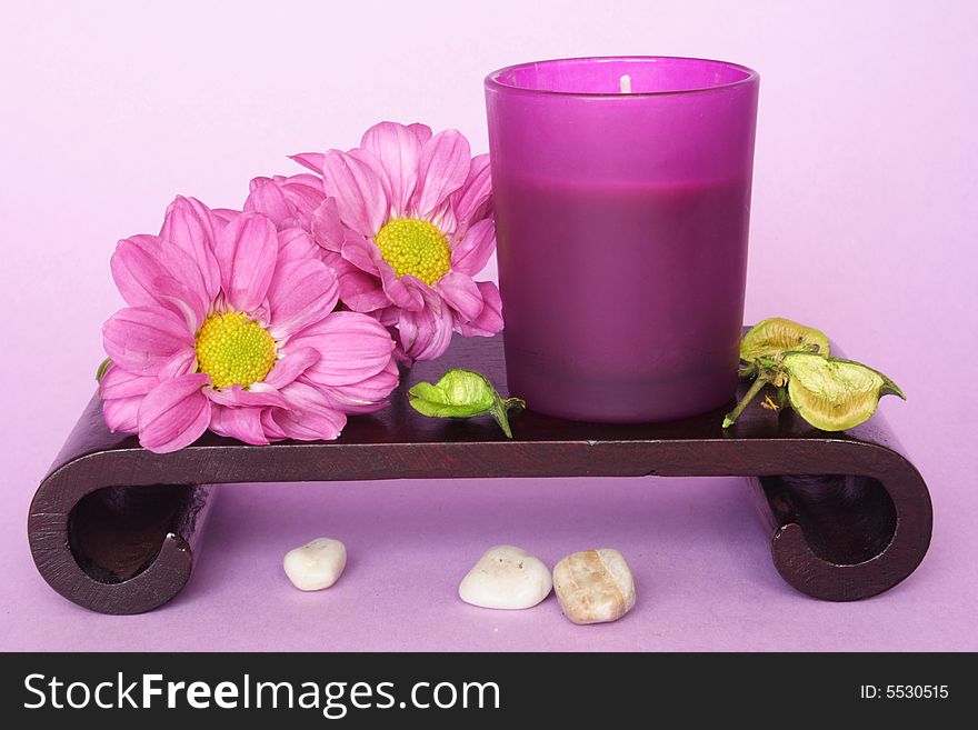 Spa candle and flowers in color background