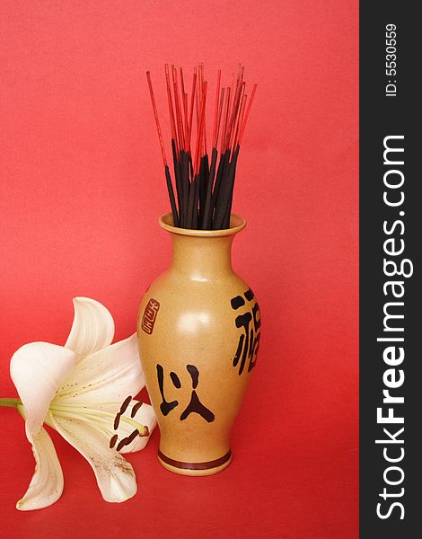 Incense sticks in a Chinese jug and Madonna lily. Incense sticks in a Chinese jug and Madonna lily