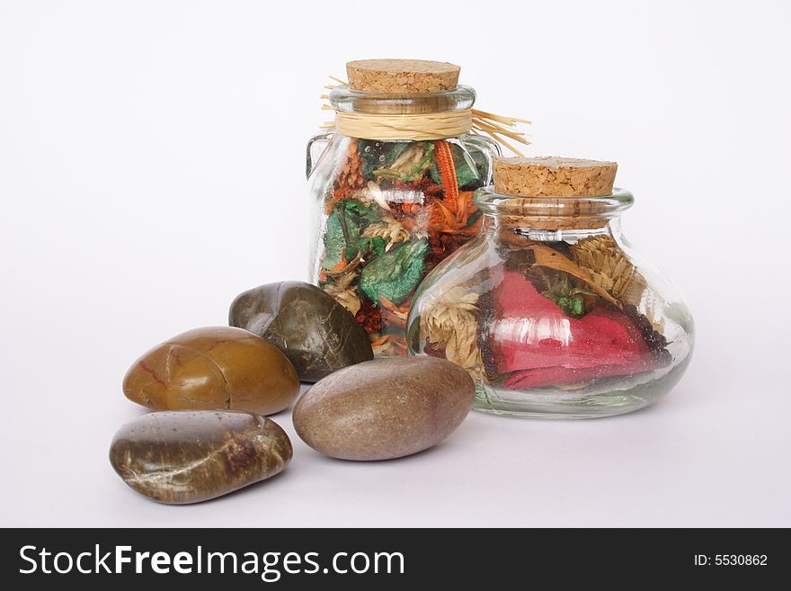 Bottles of scented flowers and pebbles isolated. Bottles of scented flowers and pebbles isolated