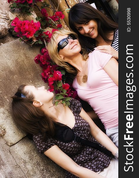 Three beautiful girl on background of a wall with flowers. Three beautiful girl on background of a wall with flowers
