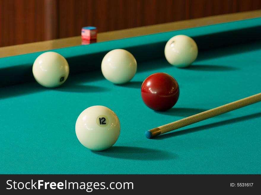 Four white billiard balls and a red ball with a cue at the green table. Four white billiard balls and a red ball with a cue at the green table