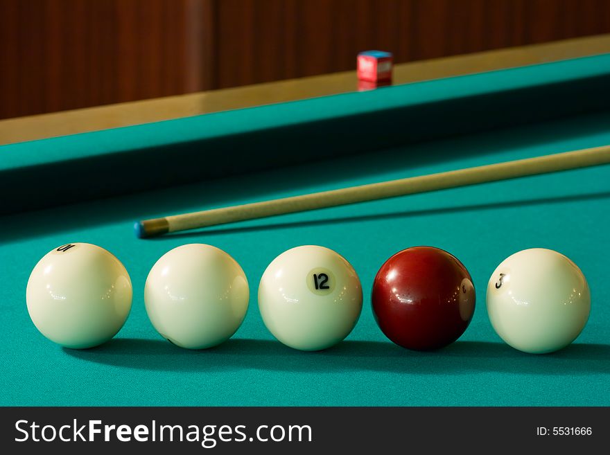 Four white billiard balls and a red ball with a cue at the green table. Four white billiard balls and a red ball with a cue at the green table