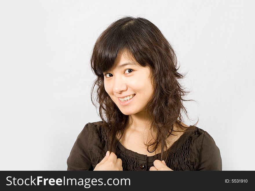 A cute asian girl wears a brown skirt with both of her hands grabbing her curved hair. A cute asian girl wears a brown skirt with both of her hands grabbing her curved hair.