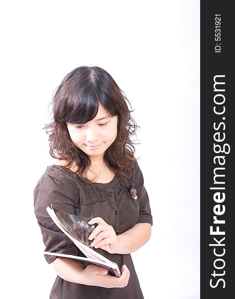 A very cute asian girl is opening a magazine to read. A very cute asian girl is opening a magazine to read