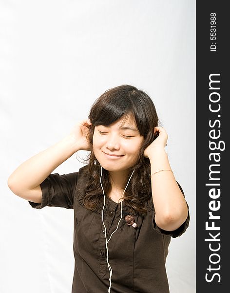 A young lady is enjoying the music through the white earphone. A young lady is enjoying the music through the white earphone