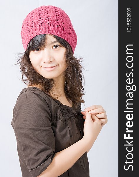 A cute asian girl wears a pink and red hat with her hands on the front. A cute asian girl wears a pink and red hat with her hands on the front