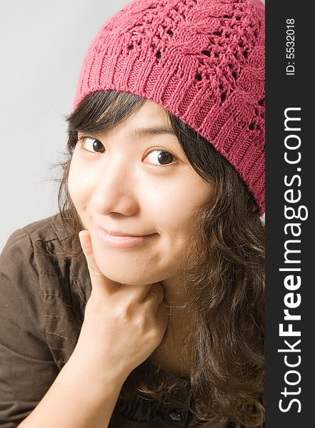 A cute asian girl with a pink hat, pointing to her mouth to offer a sweet smile. A cute asian girl with a pink hat, pointing to her mouth to offer a sweet smile