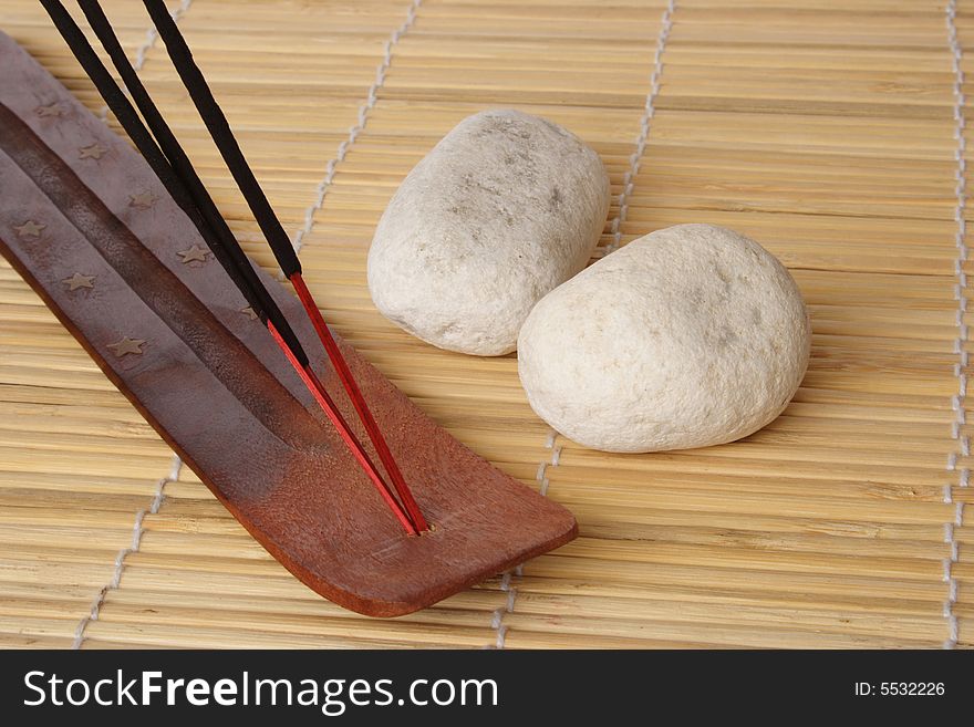 Three incense sticks and white pebbles on wood mat. Three incense sticks and white pebbles on wood mat