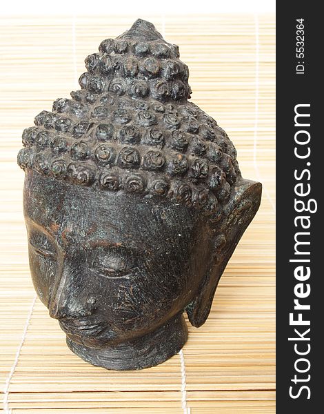 Isolated Buddha head on a wooden mat. Isolated Buddha head on a wooden mat