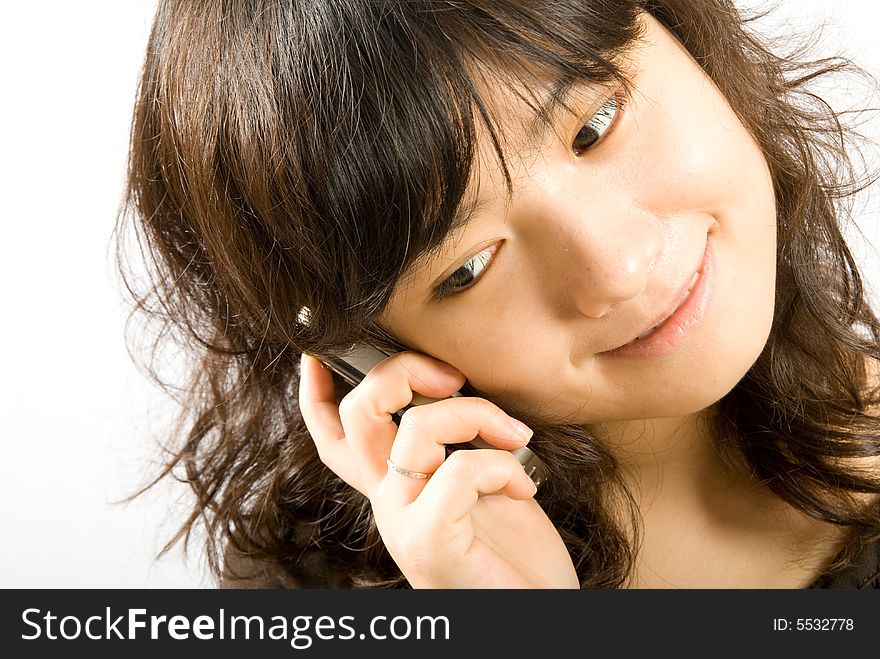 A young fashionable girl is talking to her boyfriend sweetly through a slide style hand phone. A young fashionable girl is talking to her boyfriend sweetly through a slide style hand phone.