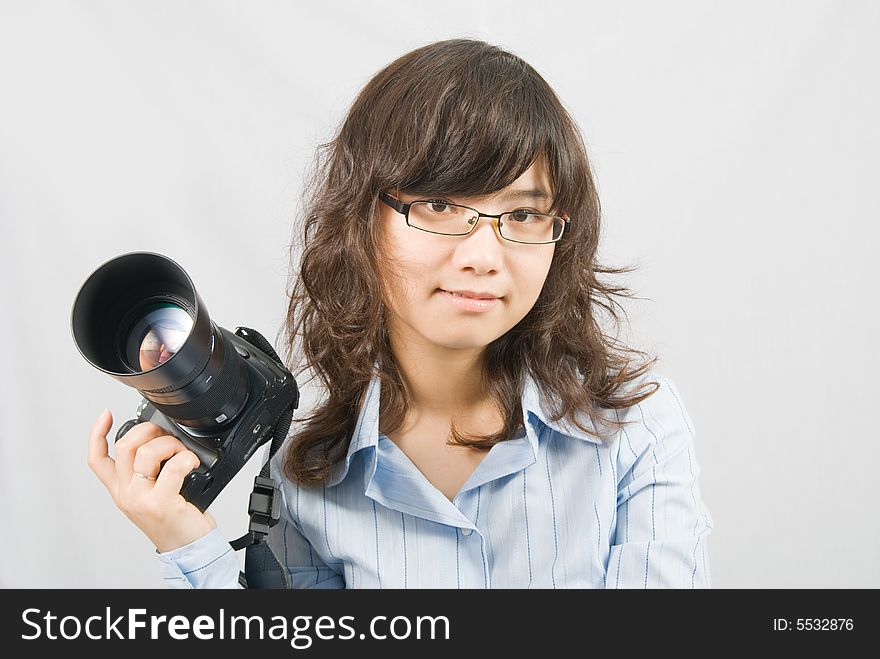 A young female photographer is holding a profession black digital camera. A young female photographer is holding a profession black digital camera