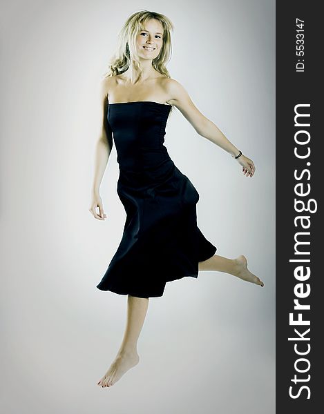 Young beautiful jumping woman wearing a black dress. Young beautiful jumping woman wearing a black dress