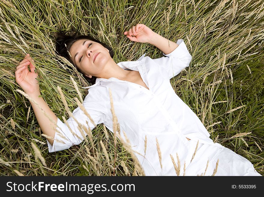 Attractive brunette woman relaxing on  meadow. Attractive brunette woman relaxing on  meadow