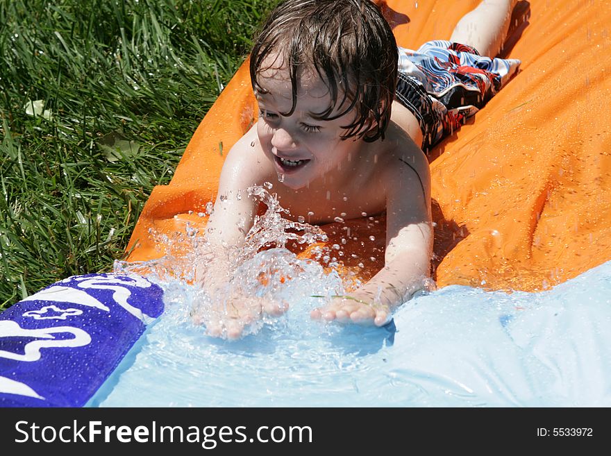 A small boy going down a waterslide. A small boy going down a waterslide