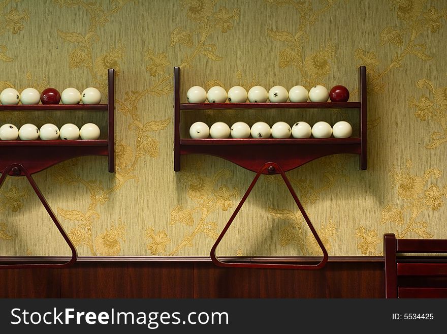 Many billiard-balls at wood shelfs at the wall in a billiard room